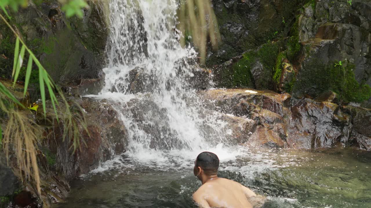 Gentle waterfall cascading over moss-covered rocks in a lush forest setting close-up
