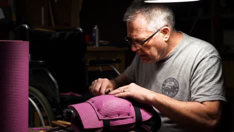 craftsman skillfully assembles innovative pink material into functional design, showcasing expert craftsmanship in a dimly lit workshop environment