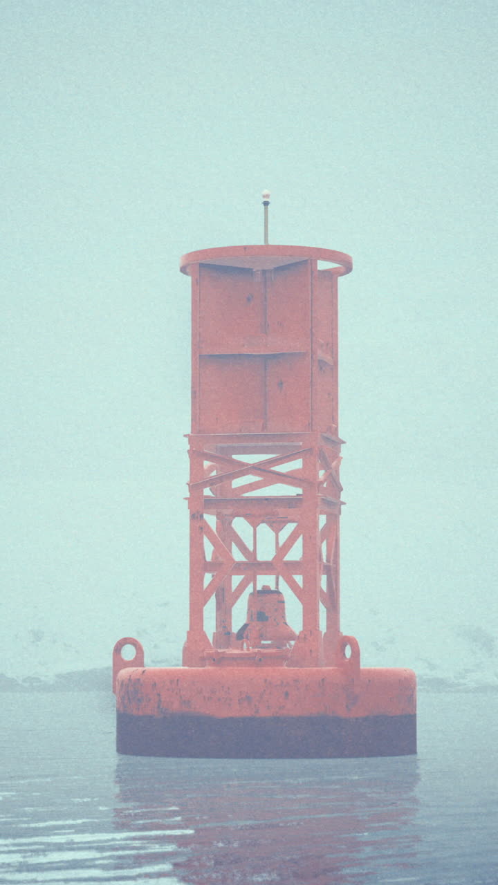 Bright orange buoy stands alone in foggy water during early morning hours