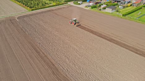 beautiful aerial of tractor plowing a empty plot of land on a sunny day