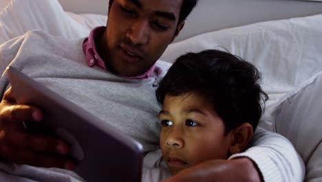 Vater-Und-Sohn-Nutzen-Digitales-Tablet-Auf-Dem-Bett