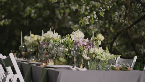 table with delicious meals and flower decoration in garden in spring day open-air event and catering