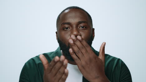 portrait of african handsome man sending air kiss to camera in studio.