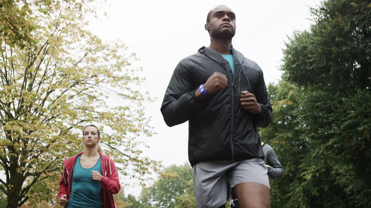 Group of runners running in park wearing wearable technology connected devices