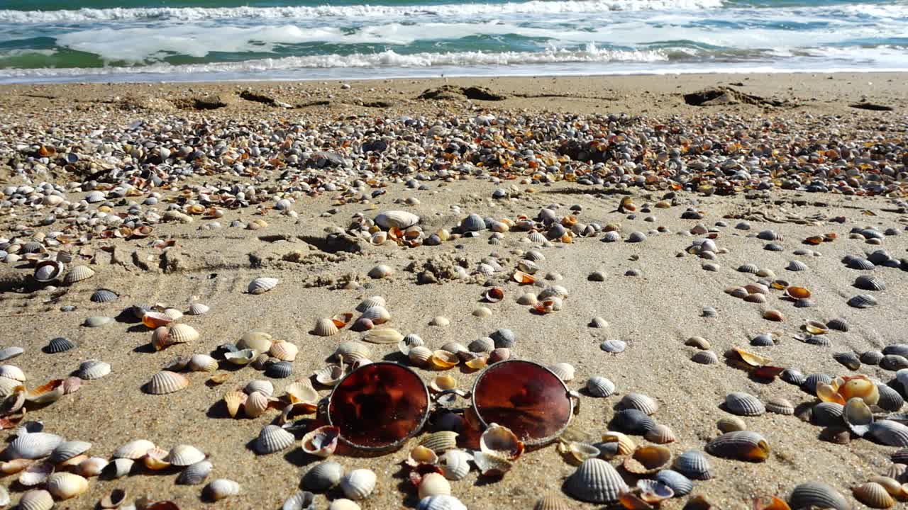Sunglasses on the sandy beach. Slow motion