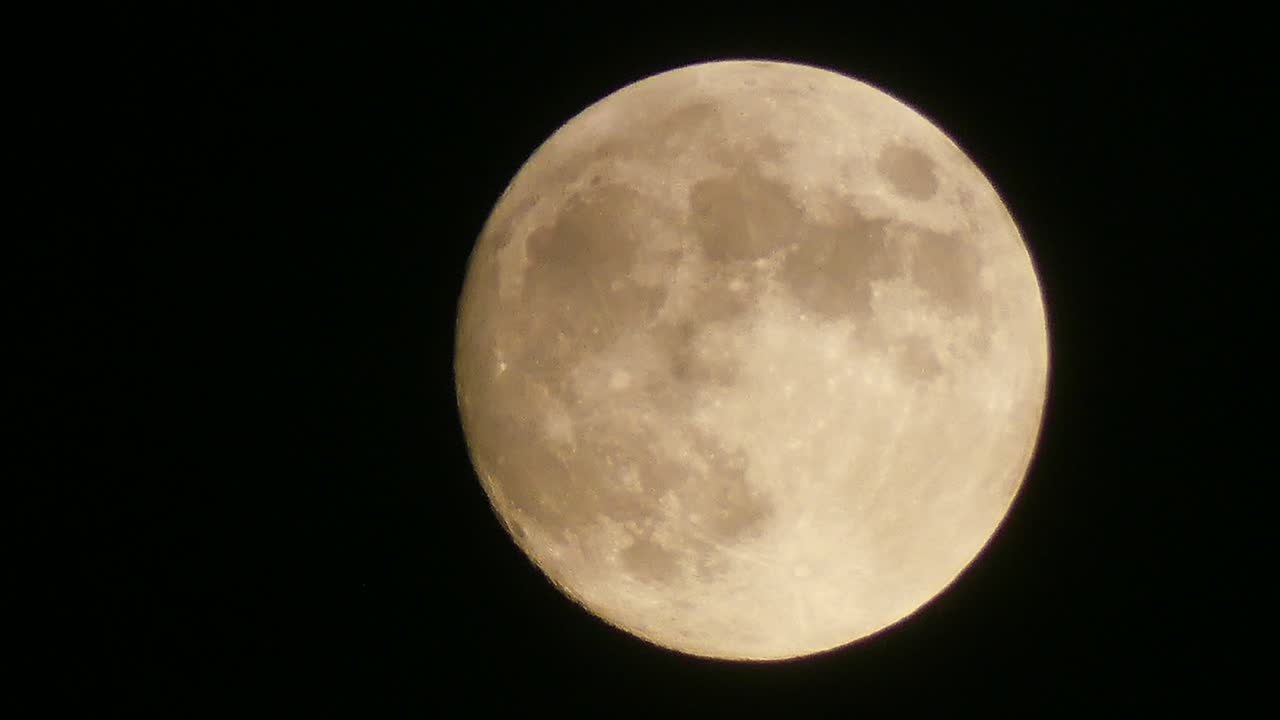 gran luna llena brillante y hermosa moviéndose lentamente de la parte inferior del cuadro a la parte superior a medida que las nubes pasan