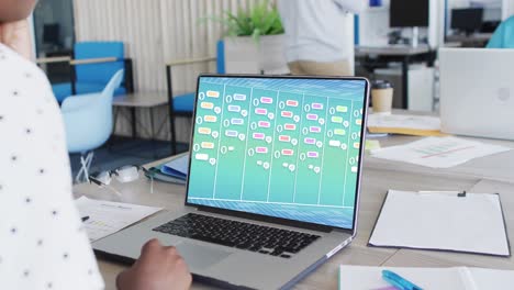 Biracial-businesswoman-in-office-using-computer-with-digital-messaging-chat-on-screen