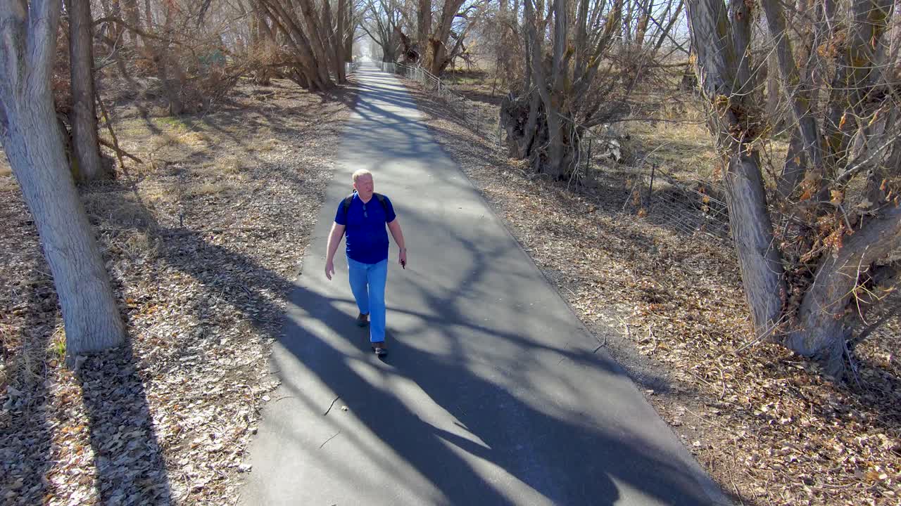 hombre mayor y maduro en una caminata por un sendero a través del bosque a principios de la primavera - vista aérea en cámara lenta
