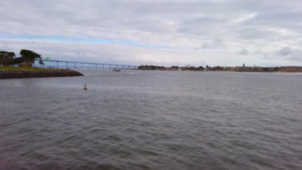 Touristic boats floating on a bay near Coronado bridge in daylight. View from the shore. Blurred shot. San Diego, California