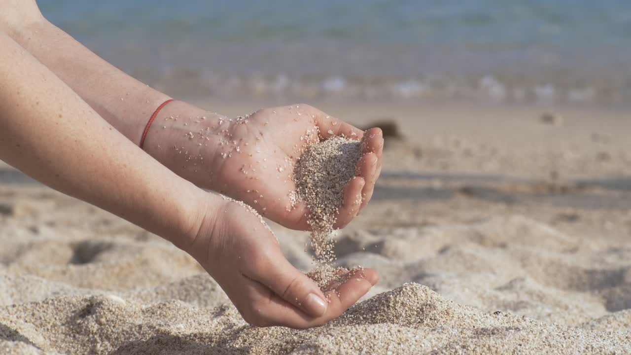 Sand falling from hand in slow motion on a beach. Vacation and travel concept. Shot on super slow motion camera 1000 fps.