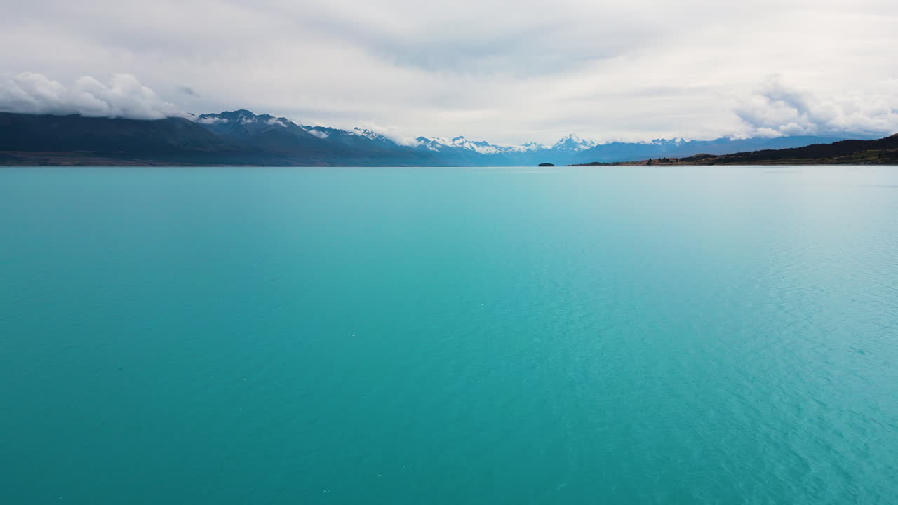 dolly aéreo sobre el agua turquesa del lago pukaki en la isla sur de nueva zelanda
