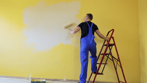 builder with paint roller. building contractor painting wall with roller brush