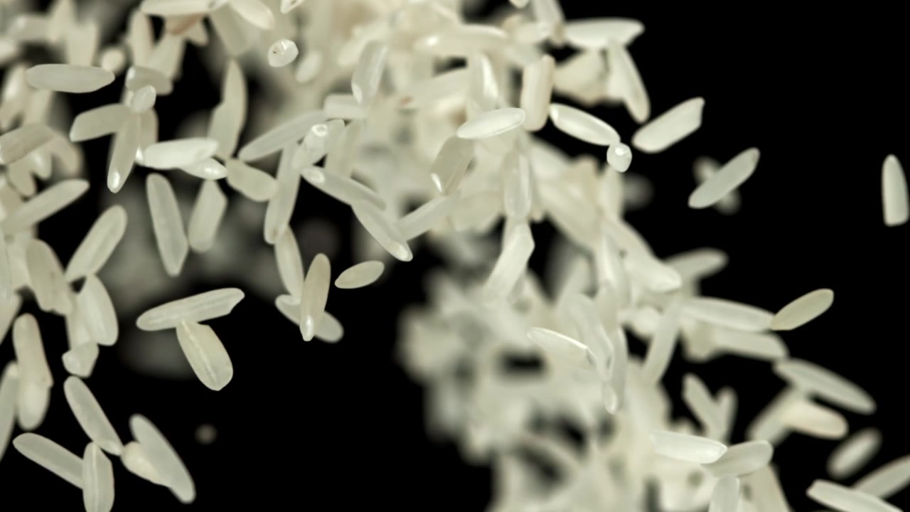 Chicchi di riso bianco che cadono al rallentatore su sfondo nero