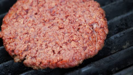barbecuing plant based impossible burger patties on electric grill close up zooming in then panning out showing 8 patties freshly placed on the grill - in cinema 4k (30fps slowed from 60fps).