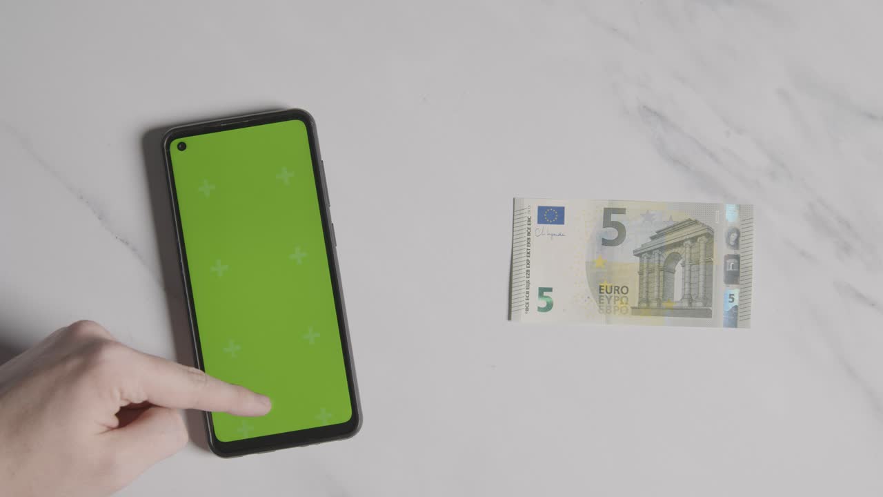 disparo aéreo de billete de 5 euros al lado de una persona que usa un teléfono móvil de pantalla verde