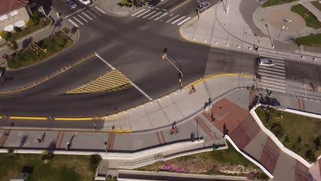 Aerial-top-down-shot-of-cyclist-riding-on-the-road-of-Mar-del-Plata,-Argentina---Beautiful-sunny-day-in-the-evening-on-walkway-beside-sandy-beach