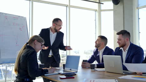 group of young entrepreneurs indoors. successful man talking to his partners giving his ideas. business people sitting at the table and listen to their boss in office.