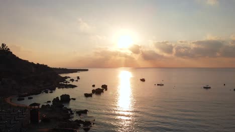 rising aerial shot over a golden sunset beach at konnos bay