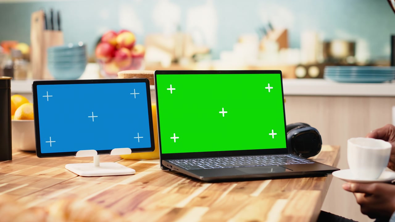 Giovane donna con laptop con schermo verde e tablet con schermo blu