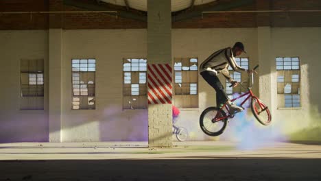 jinetes de bmx en un almacén vacío usando una granada de humo
