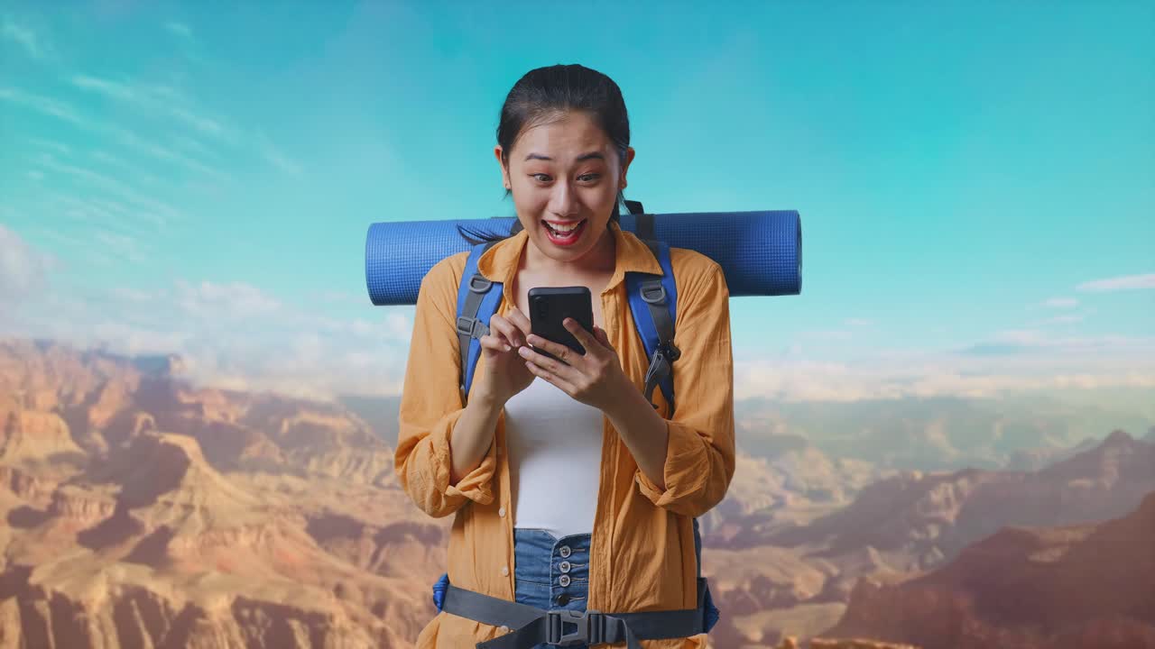 Asian Female Hiker With Mountaineering Backpack Looking At The Smartphone And Saying Wow While Traveling At The Top Of Mountain