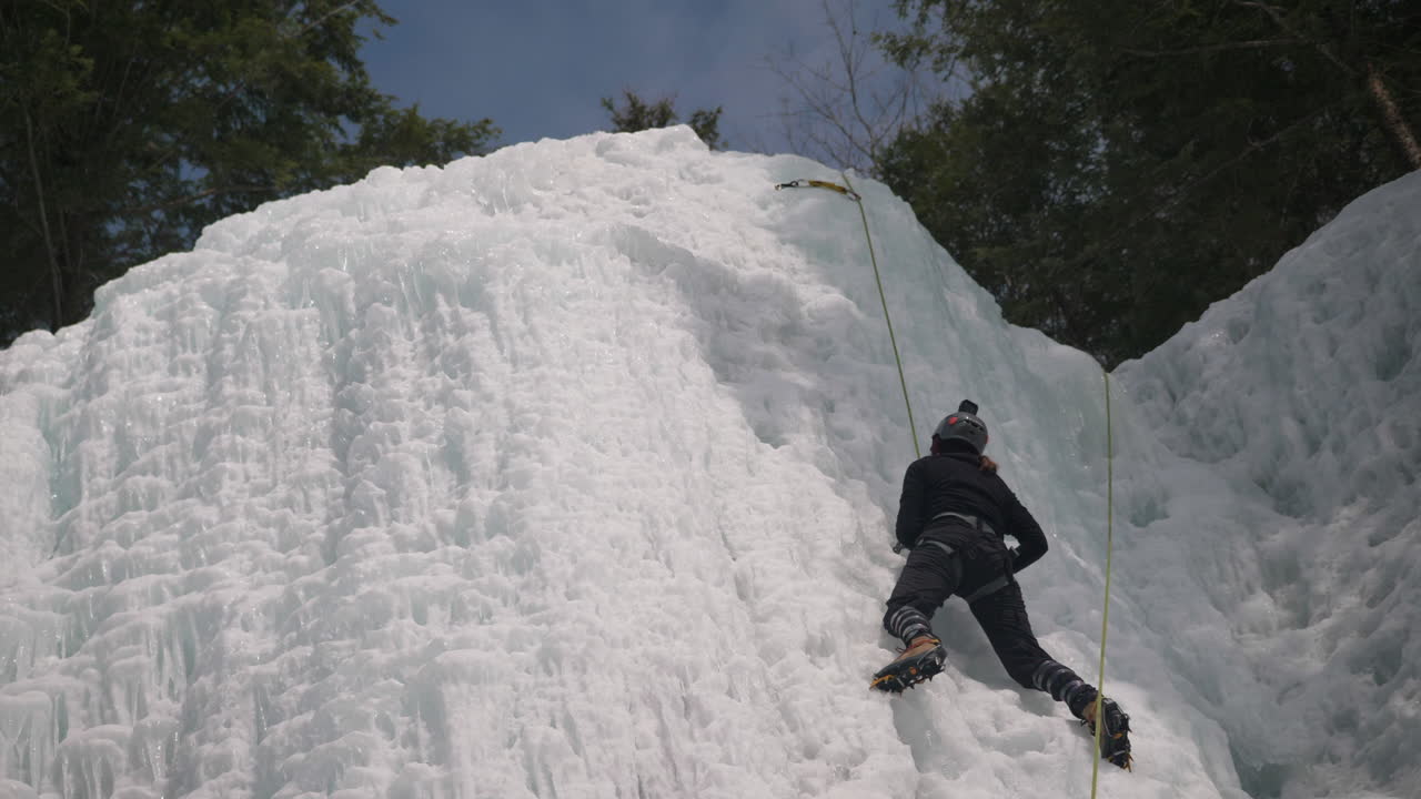 un escalador de hielo aventurero intenta escalar una pared rocosa cubierta de hielo