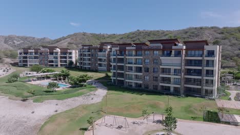 Aerial-view-of-luxury-apartment-hotels-with-swimming-pool,-garden-and-beach-during-sunny-day-in-Bani,-Dominican-Republic