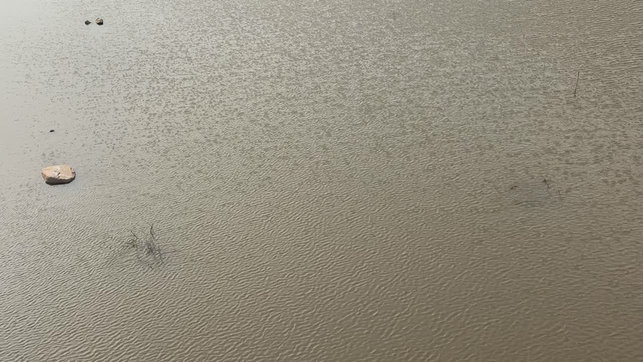 Wind passing throught water of lake near mountain