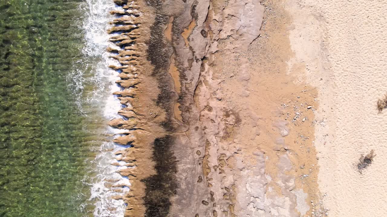 clip aéreo de drones sobre una playa con olas aplastando las rocas en la orilla en kavala, macedonia, grecia
