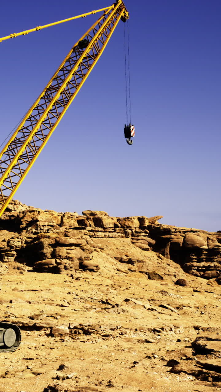Una squadra di costruzione utilizza una gru per sollevare attrezzature in una località desertica.