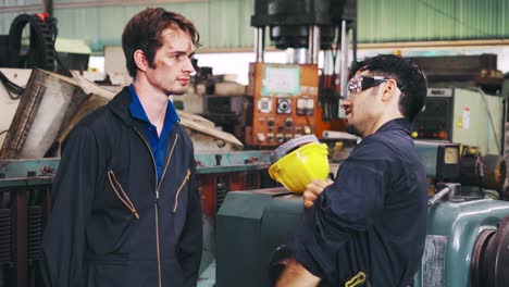 tired factory workers taking a break and talking to coworker in the factory