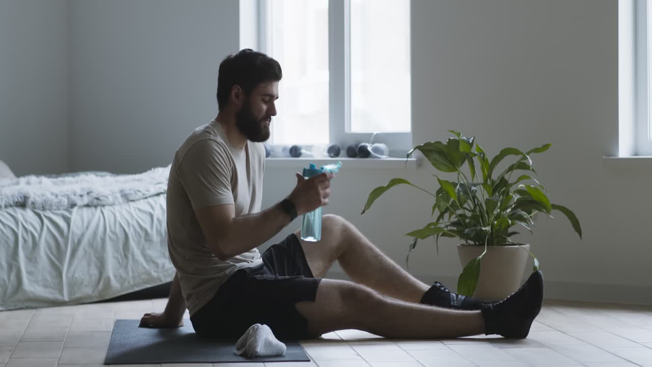 hombre descansando después de un entrenamiento, bebiendo agua