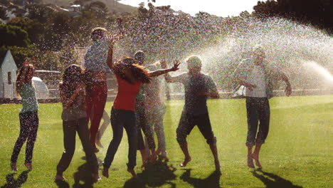 students messing around in the sprinklers on the grass