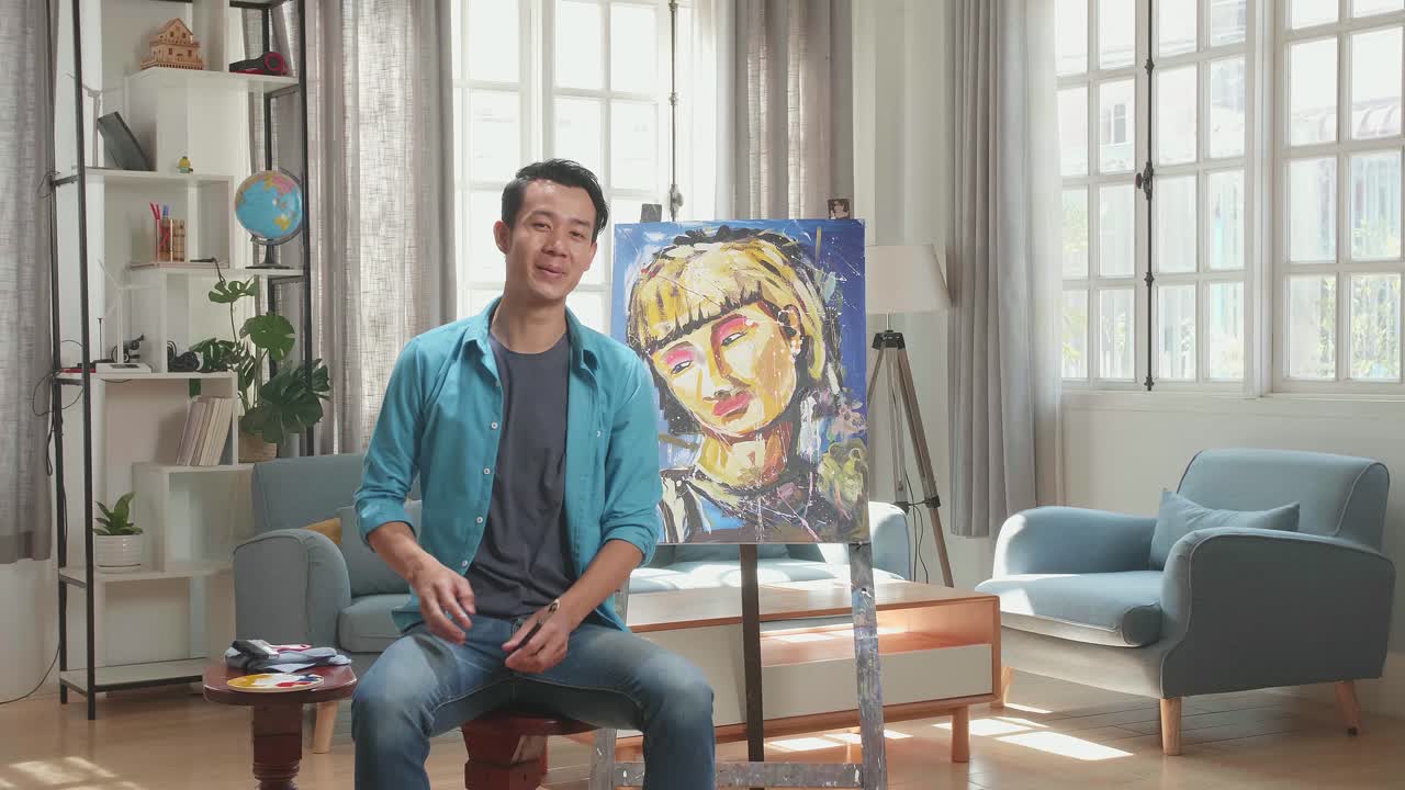 Asian Artist Man Sitting On Round Wooden Chair Without Backrest Holding Paintbrush Mixed Colour Wipe The Sweat Before Crossing His Arms And Smiling After Finish Painting A Girl On The Canvas