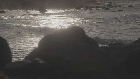big waves crashing on the beach near reve havn borestranda norway during sunset with the beach and sea in the background and the sun reflection in the water with rocks in the foreground log