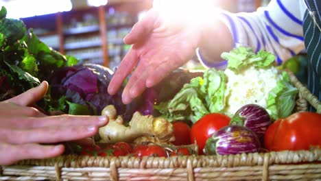 male staff assisting woman in selecting fresh vegetables