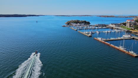 speedboat leaving wake in surface of blue sea passing by marina at lysekil in sweden