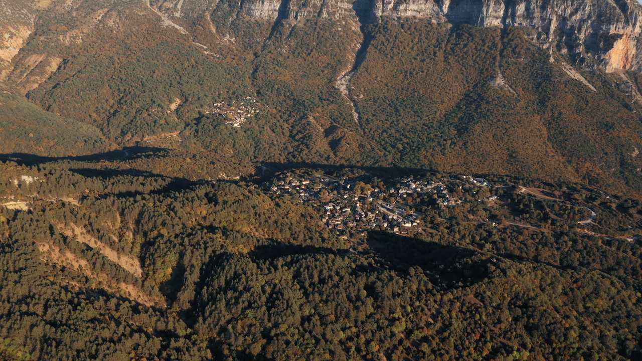Limestone cliffs and mountain slopes above Mikro Papigko village in Zagorochoria Epirus Greece aerial landscape establishing