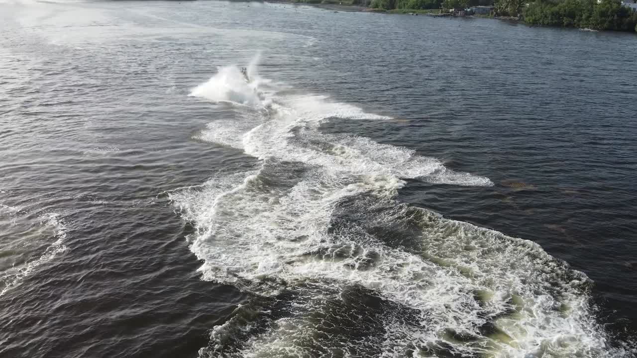 Bird's eye view Drone flight behind a jetsky traveling over the water in fast left and right curves