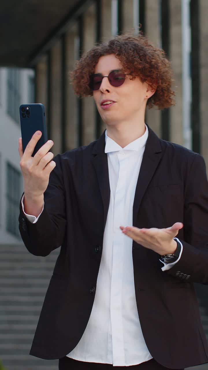 Uomo d'affari che fa una telefonata, una conversazione online, un altoparlante che parla, che saluta fuori dall'ufficio.