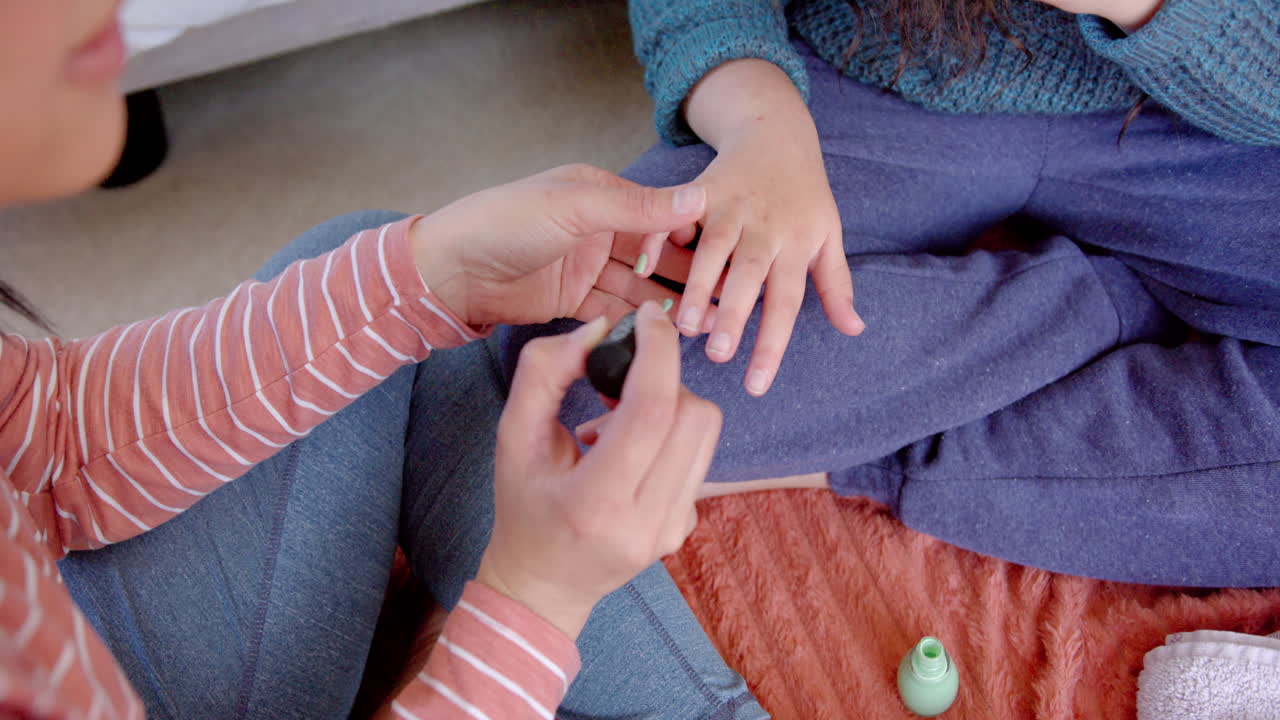 빛 이 있는 방 에서 딸 의 손 을 칠 하고 앉아 있는 양족 어머니