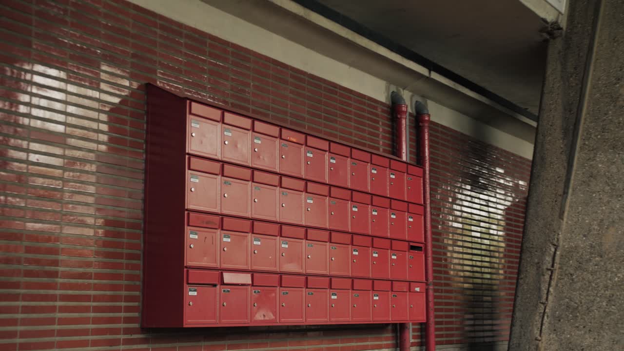 Revealing gimbal shot of red mailboxes on a tiled wall in an urban residential area