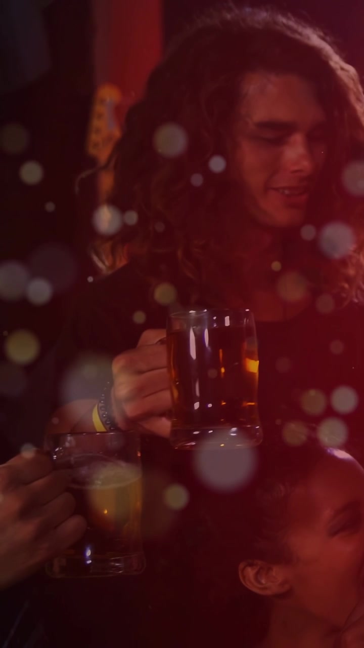 Video verticale: Uomo che alza un boccale di birra dopo l'ingresso delle mani, dando il via a un brindisi al bar tra un bokeh sfocato.