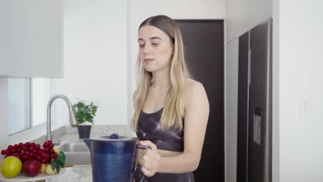 joven atlética hace un batido de jugo saludable para la dieta en la cocina