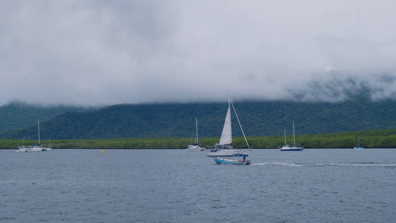 조용 한 바다 에서 작은 색 항해 보트 가 지나가고, 승무원 들 은 항해 보트를 내려 놓는 일 에 몰두 하고 있다