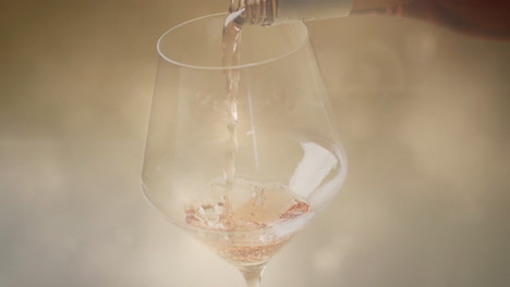 composite of white wine being poured into glass over spots of light background