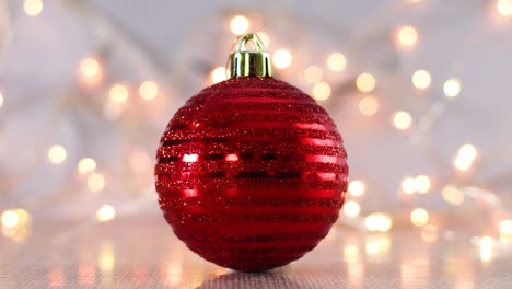 bola de adorno roja de navidad con luces parpadeantes detrás