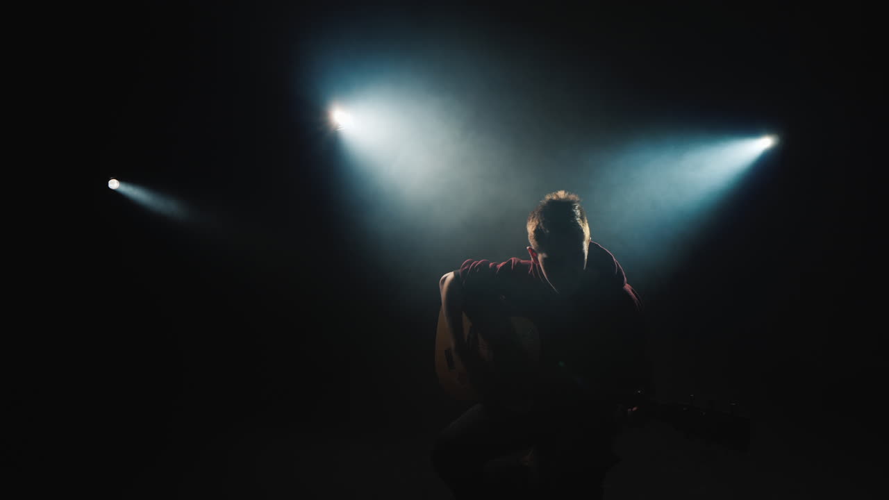 un joven toca la guitarra sentado en el escenario 3