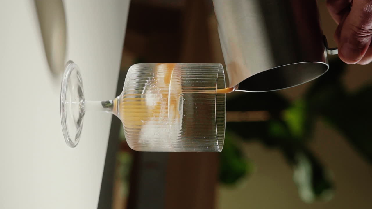 여름에 집에서 상쾌한 에스프레소 토닉을 만들기 위해 각얼음과 토닉 워터로 마시는 유리에 커피를 붓는 수직 비디오