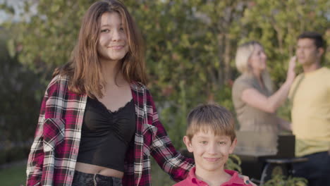 Happy-teenage-girl-standing-with-her-preteen-brother-outdoors